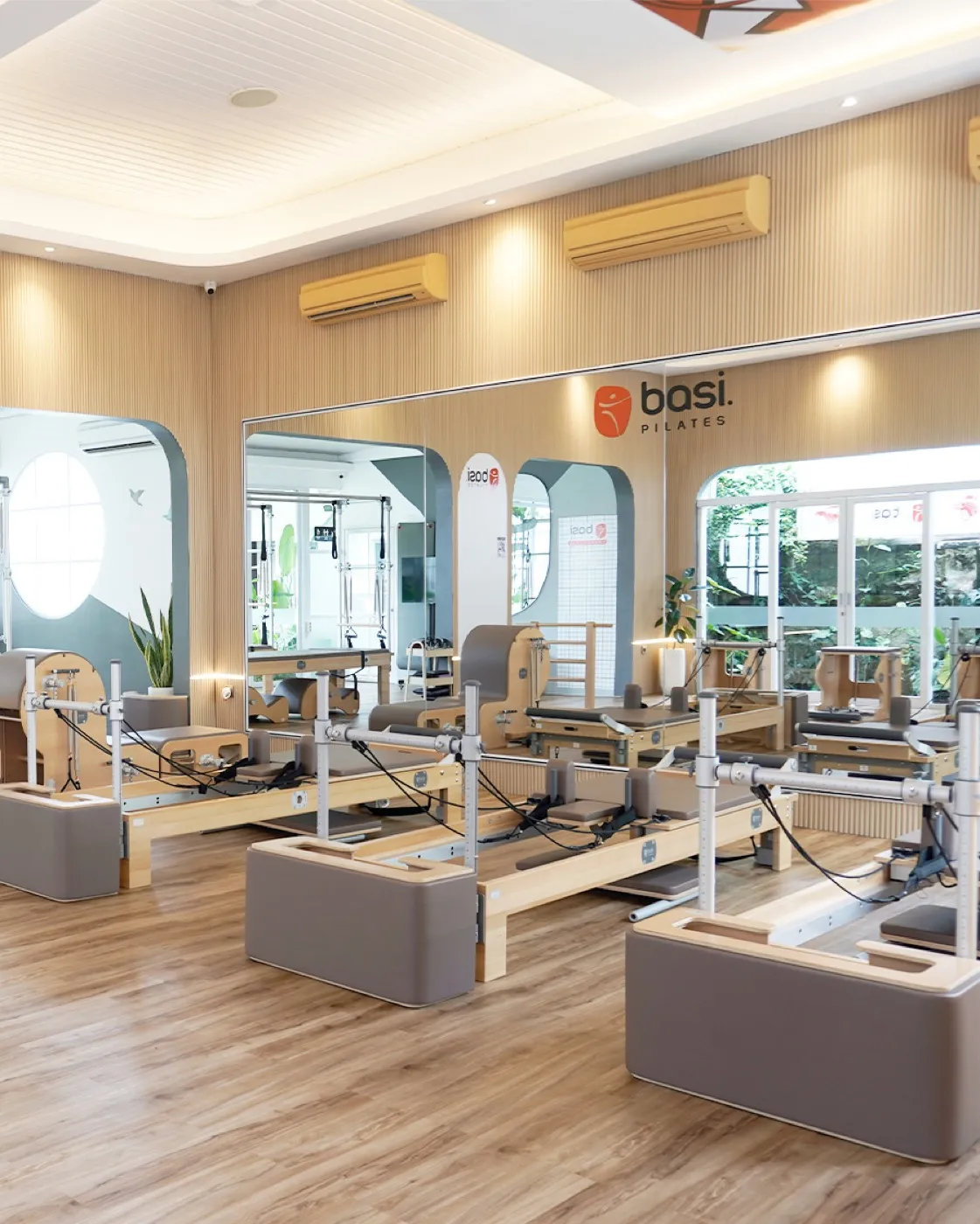 Ruang studio BASI Pilates Yogyakarta yang terang dan bersih, deretan reformer menghadap taman